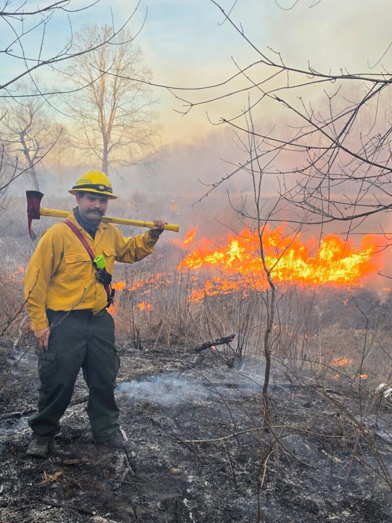 Firefighter in Wildland clothes, standing in front of fire